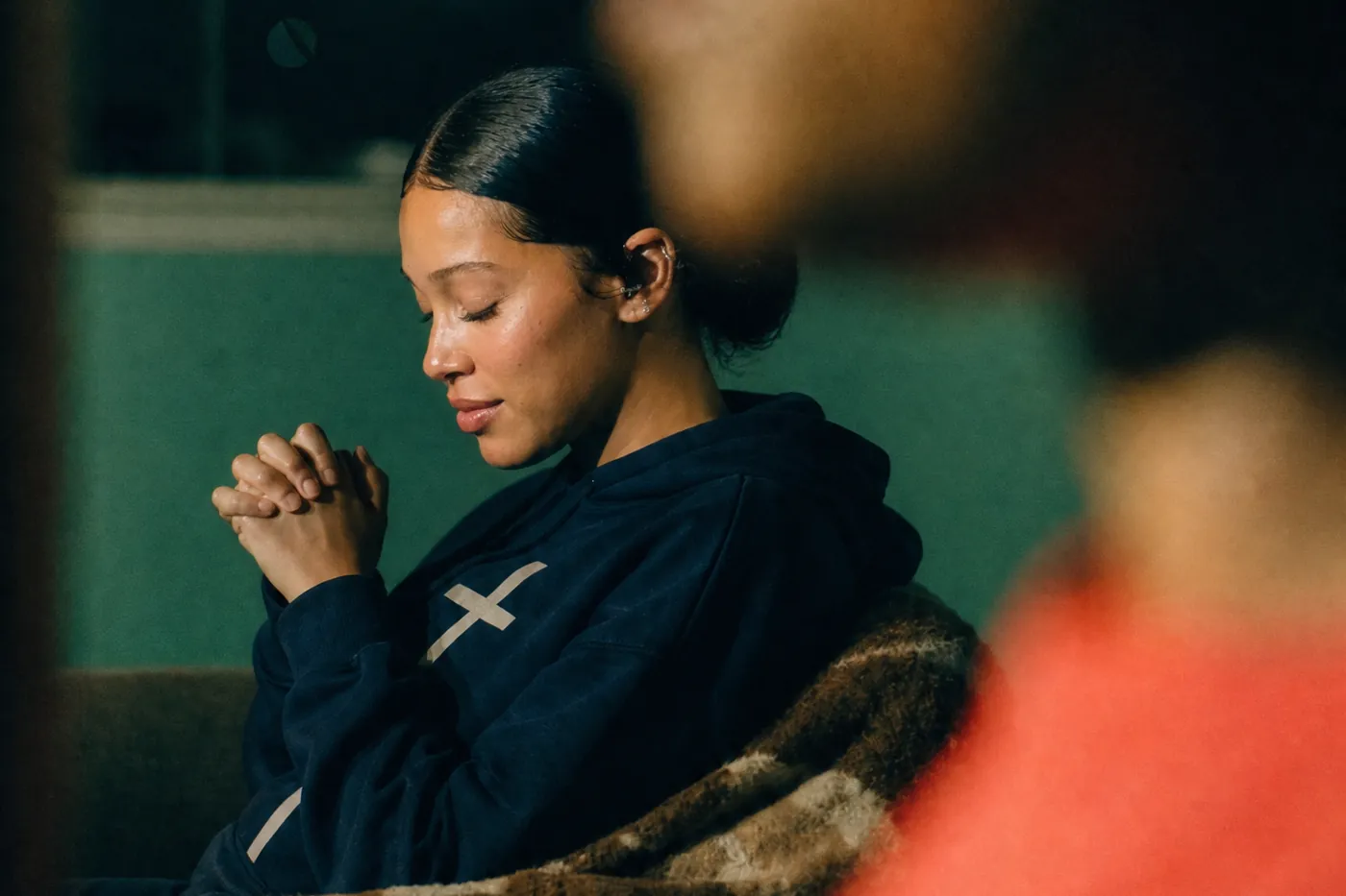 A young woman sitting with her hands folded in prayer